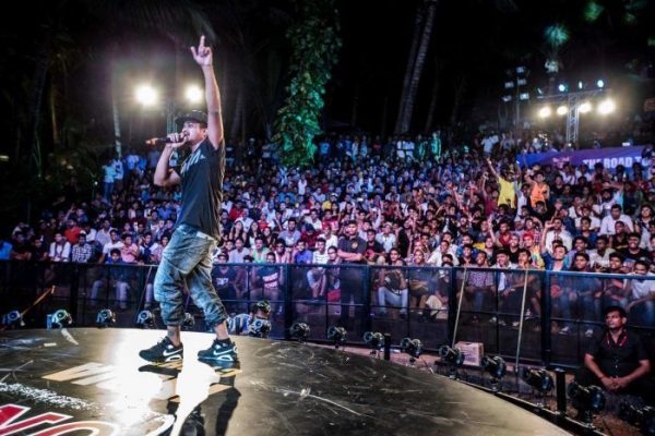 A Lead Vocalist Performing On The Grand Musical Stage Infront Of The Mass Crowd.